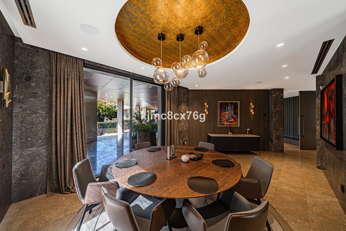 Luxe eetkamer met ronde tafel, design verlichting en schuifpui naar de tuin.