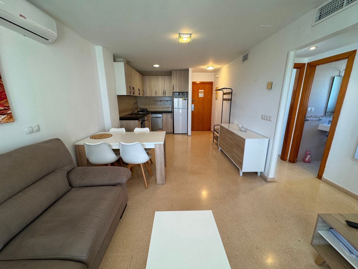 An open-plan living, dining, and kitchenette area with a sofa, dining table, and modern kitchen cabinets.
