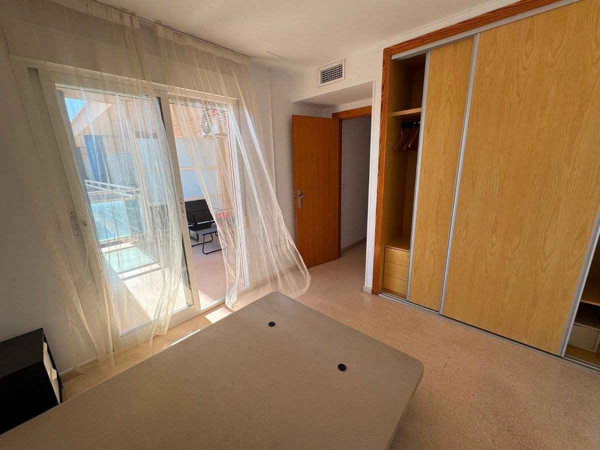 Bedroom with a balcony door showing outdoor seating and a large wooden wardrobe with sliding doors.
