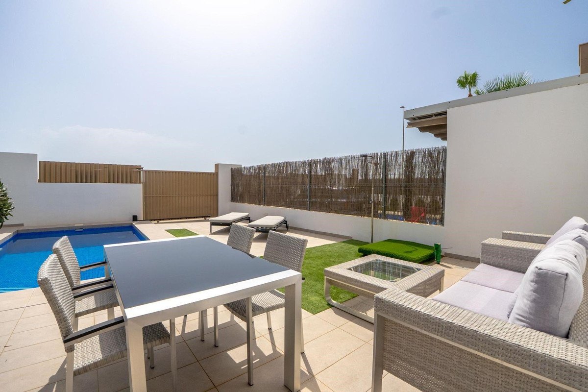 Outdoor patio with a swimming pool, dining table, lounge chairs, and a sofa with a coffee table.