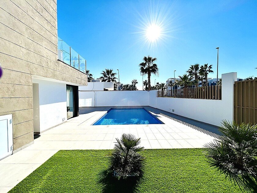 Modern villa with a swimming pool, sunlit patio, and palm trees.