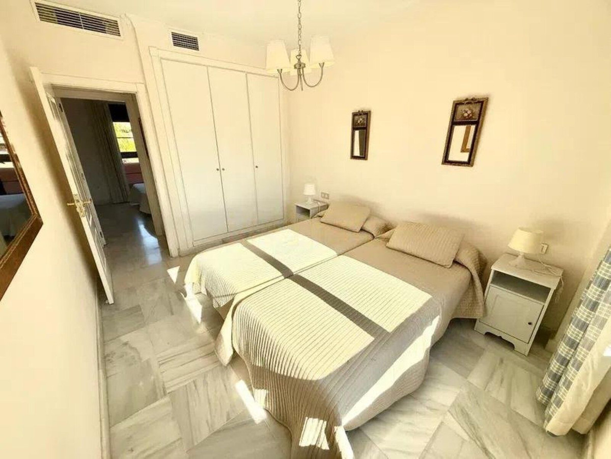 Slaapkamer met twee eenpersoonsbedden, nachtkastjes en witte kasten.