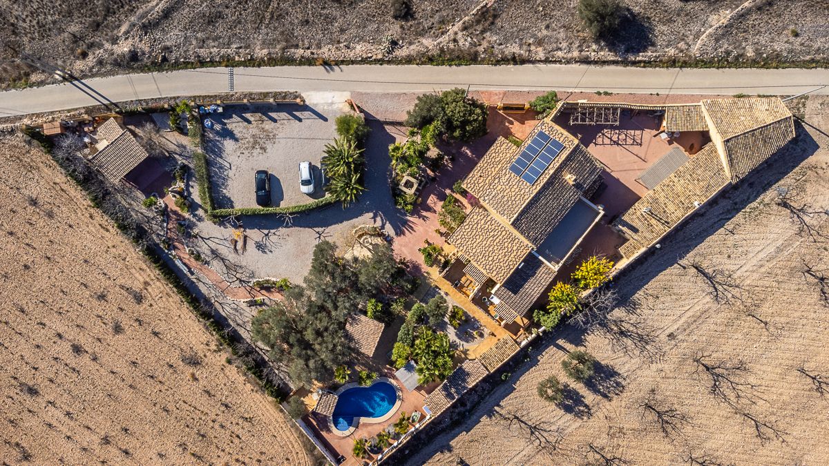 Luchtfoto van een landelijke villa met zwembad en zonnepanelen.