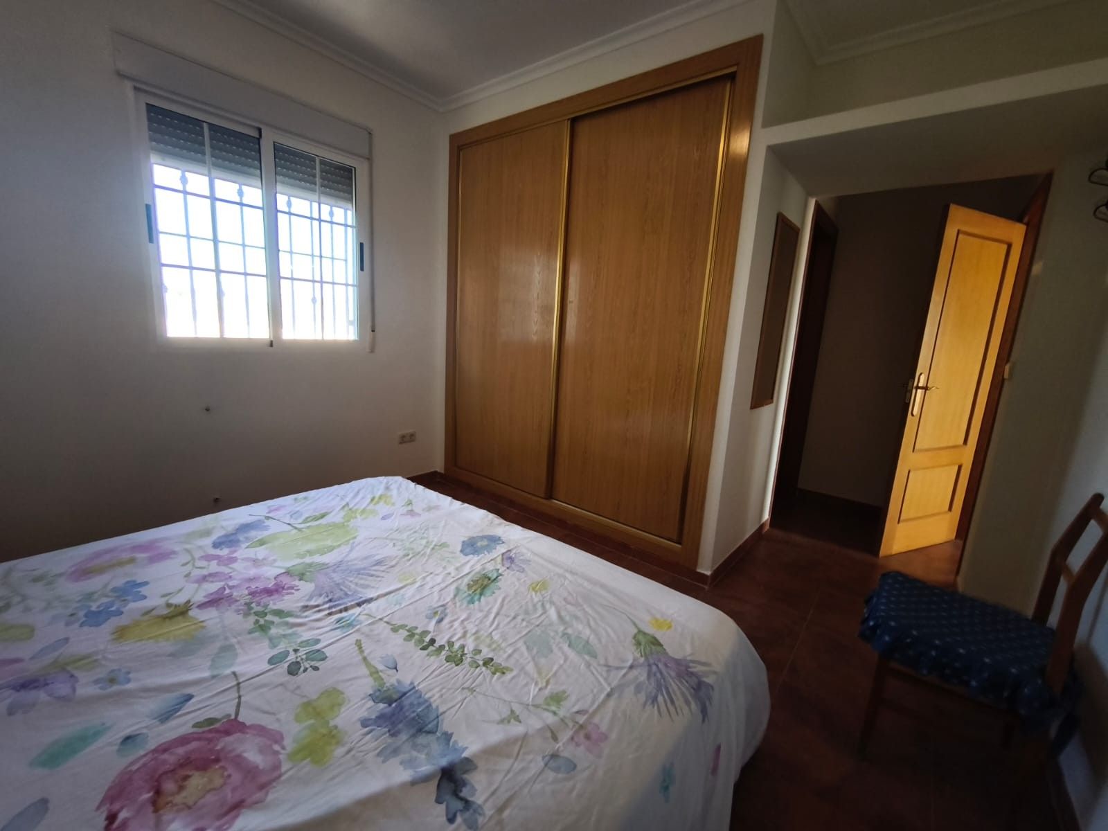 Slaapkamer met bed, kast, raam, deur en stoel