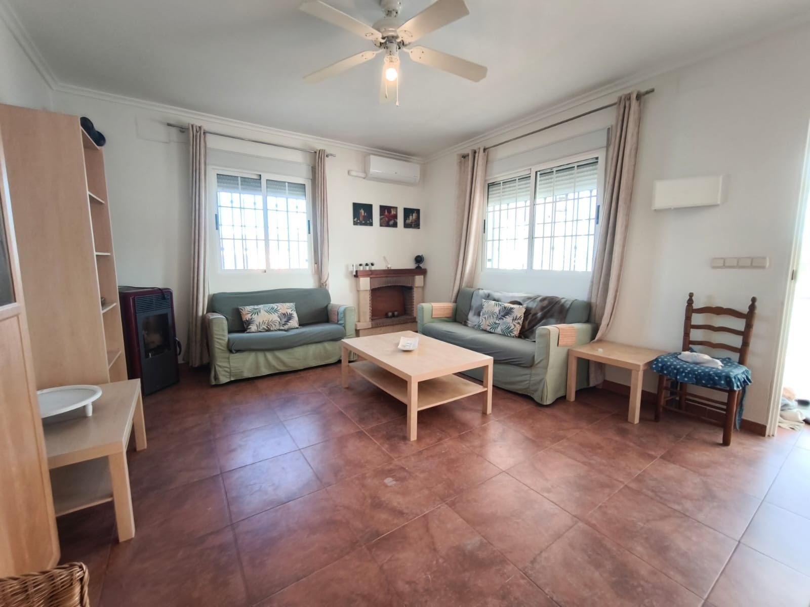 Gezellige woonkamer met groene banken, houten tafel en open haard.