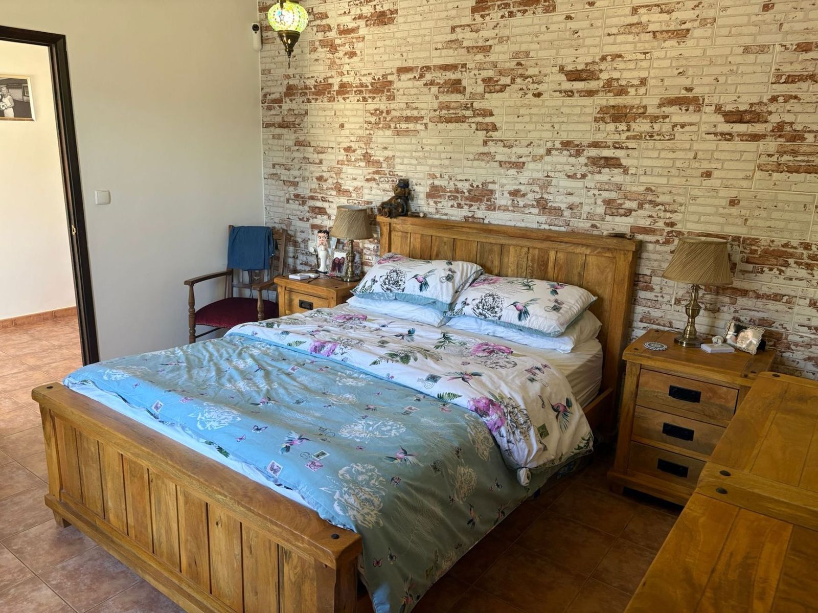 Gezellige slaapkamer met houten bed en bakstenen muur