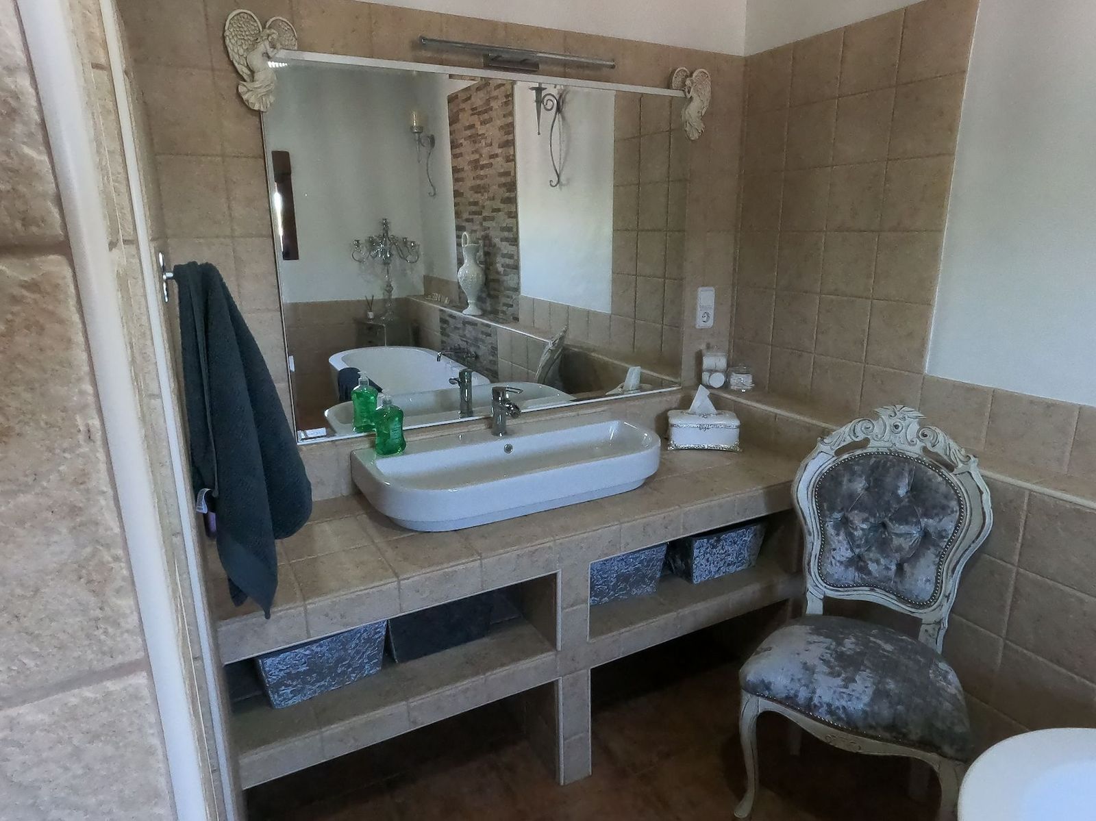 Badkamer met wastafel, tegels en een antieke stoel