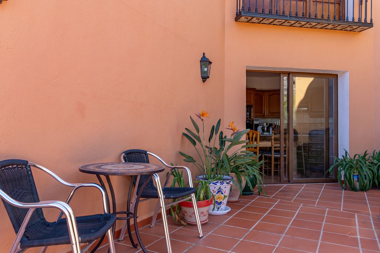 Buitenpatio met tuinmeubilair en planten bij een gebouw.