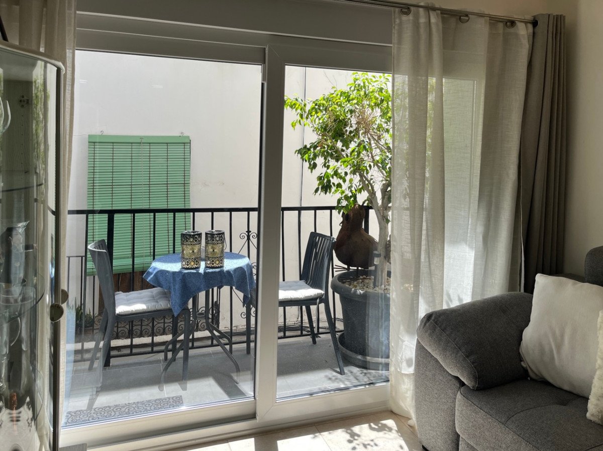 Balcony with bistro set, potted plant, and decorative items, viewed from the living room.