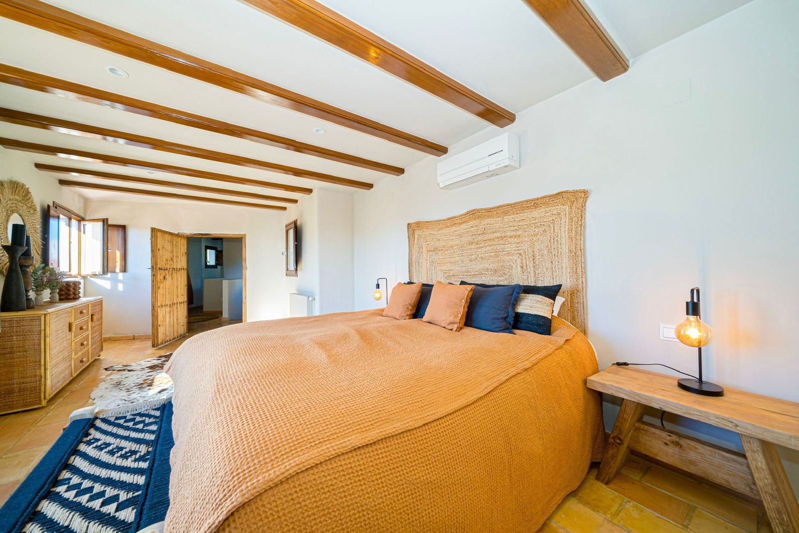 Rustieke slaapkamer met houten balken plafond en okerkleurig beddengoed