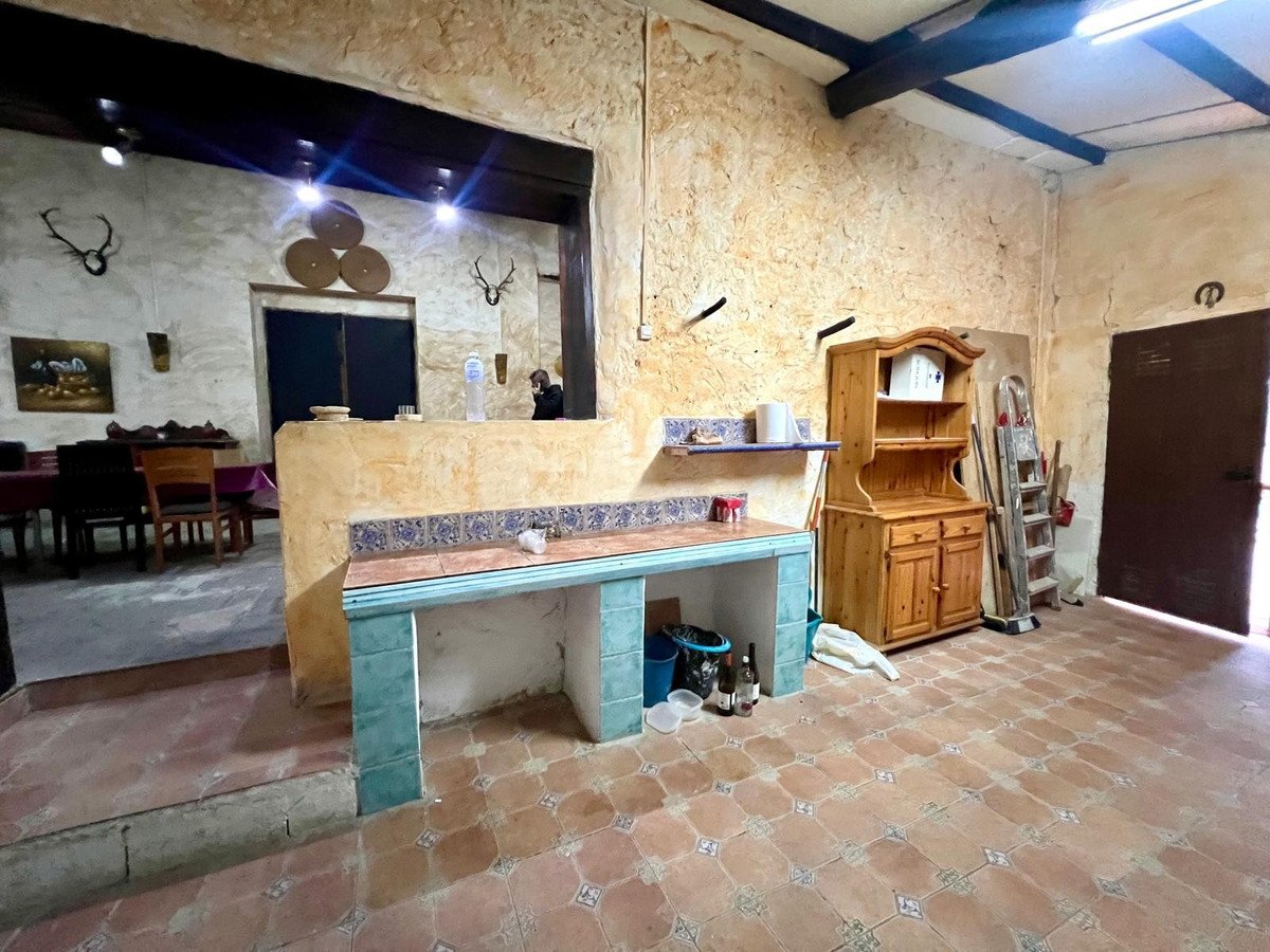 A rustic kitchen area with a tiled countertop and wooden cabinets, decorated with animal mounts and decorative plates on the wall.