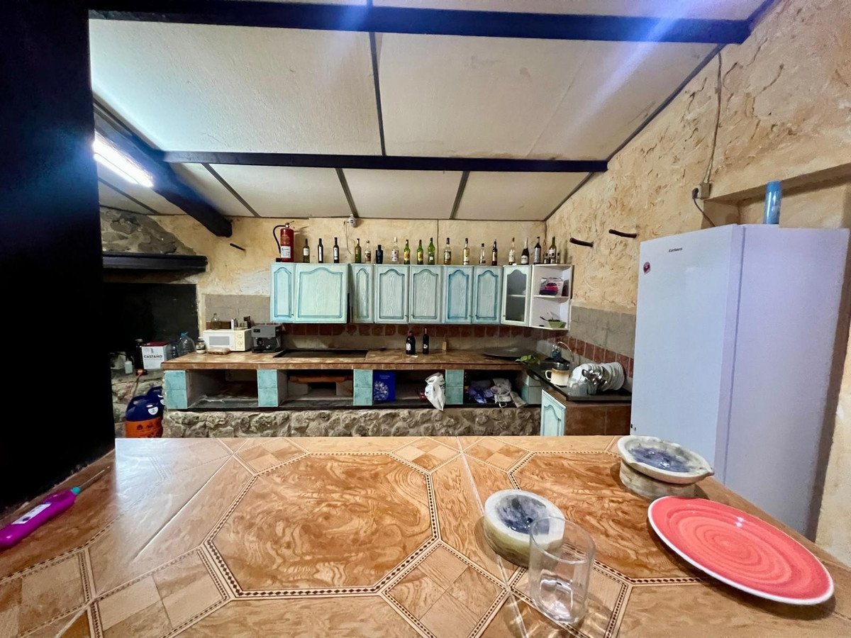 A spacious country kitchen with light blue cabinets, a white refrigerator, and a large tiled countertop.