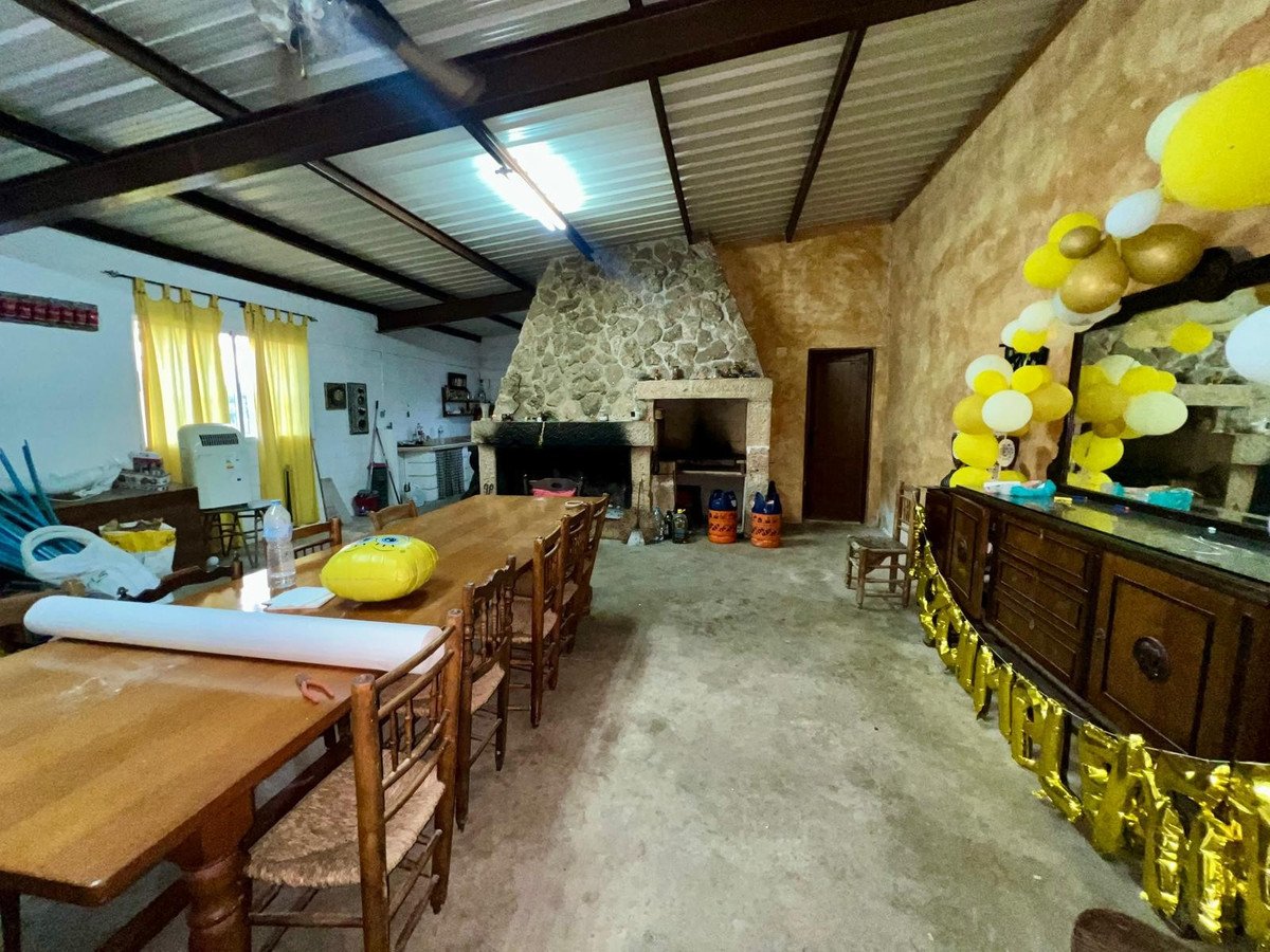 Spacious dining area with a large wooden table, stone fireplace, and festive yellow balloons and banners.