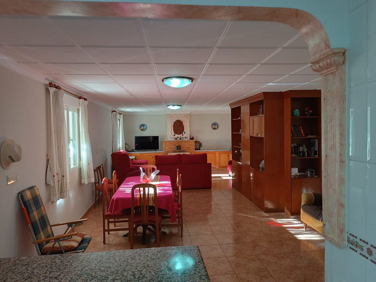 Spacious living and dining area with red furniture, a dining table set for four, and large wooden built-in shelves.