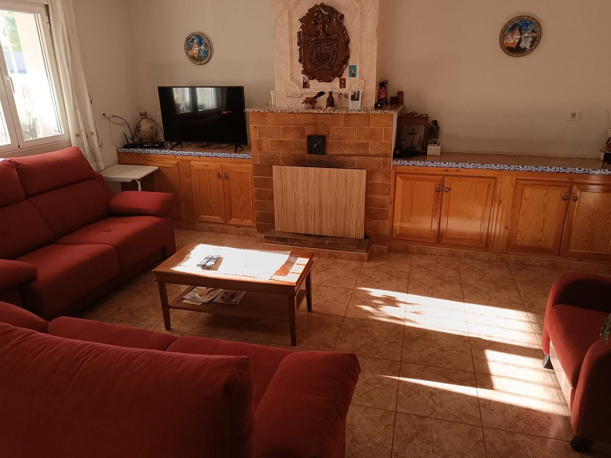Living room with red sofas, a coffee table, built-in cabinets, and a decorative brick fireplace with a television above.