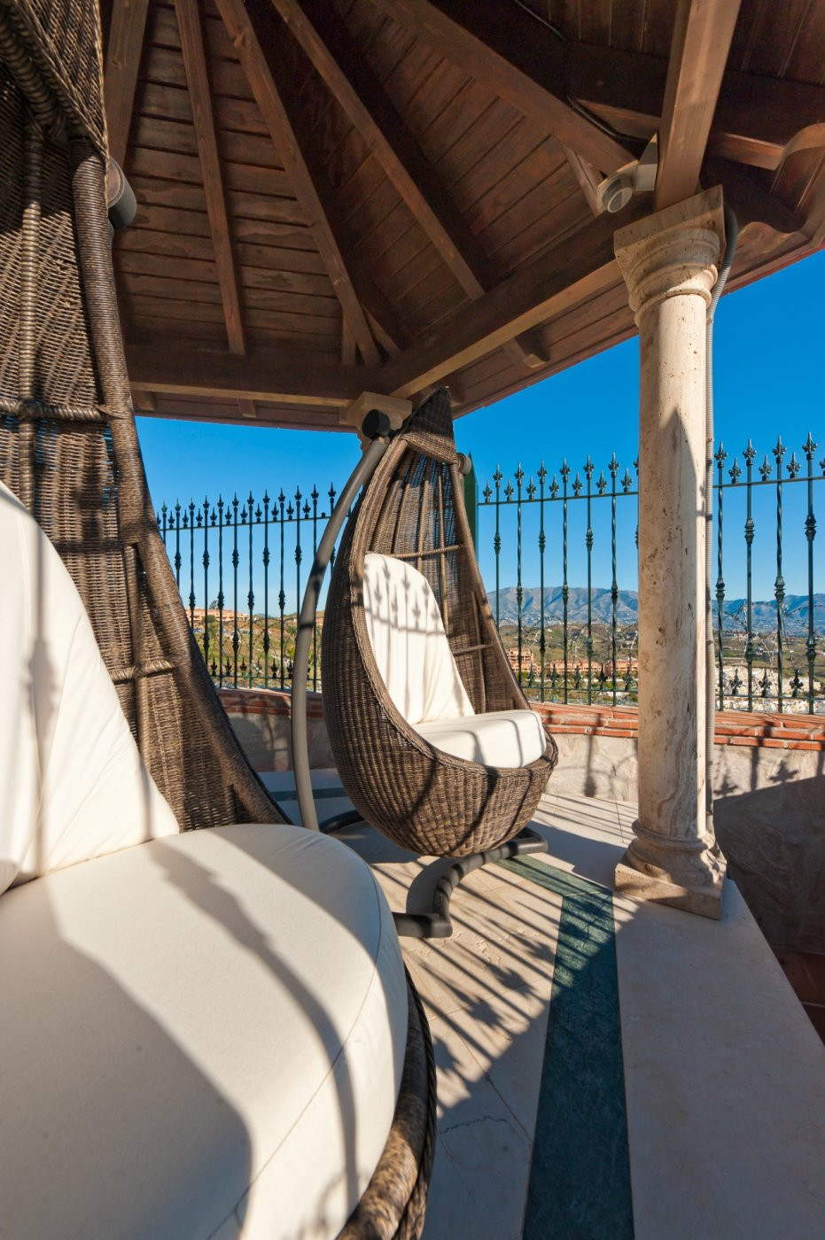 Rieten hangstoel op terras met uitzicht op de bergen.