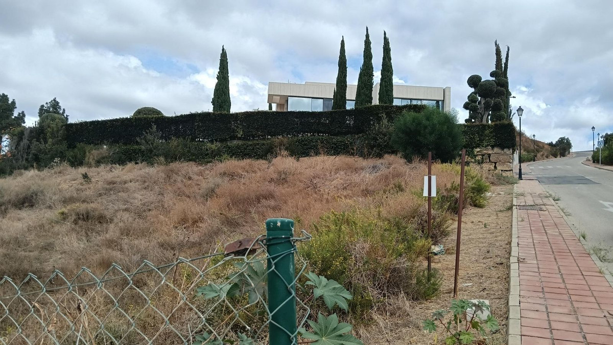 Exterieur van moderne villa met droog landschap en groene bomen.