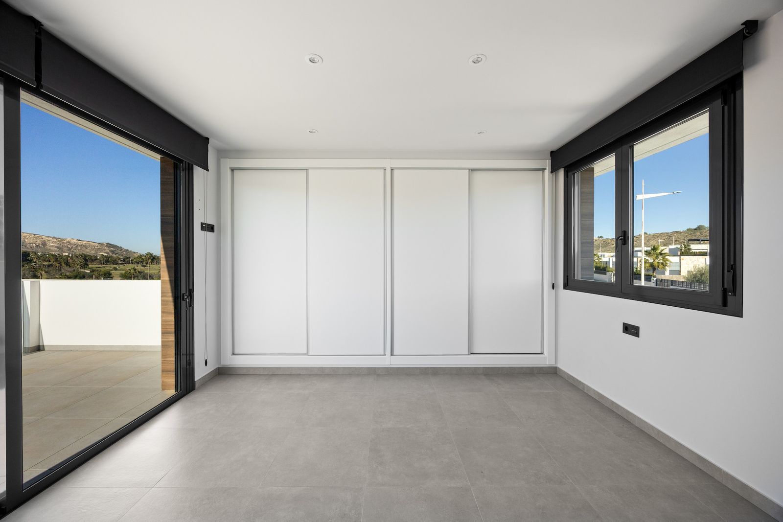 Lichte slaapkamer met schuifdeurkast en uitzicht.