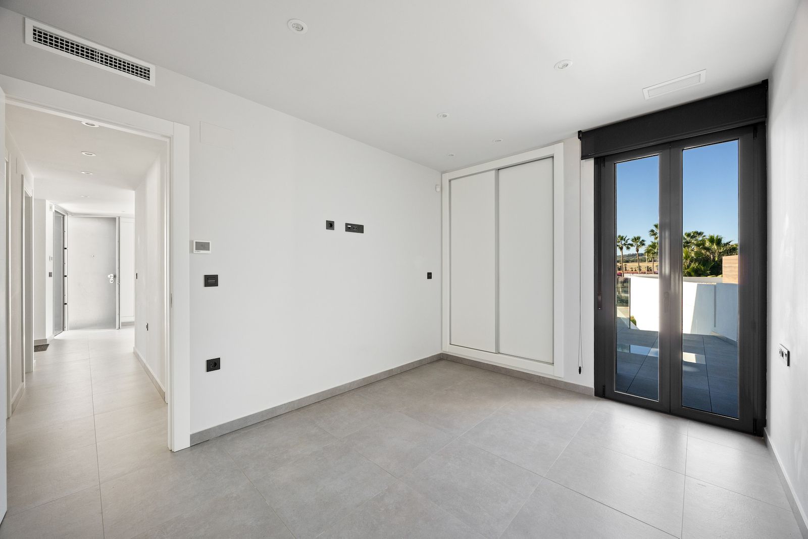 Moderne minimalistische slaapkamer met balkonuitzicht en schuifdeurkast.