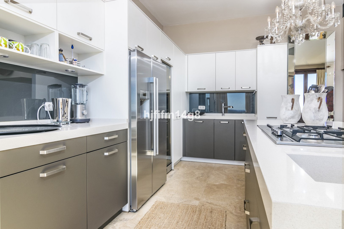 Moderne keuken met grijze en witte kasten, roestvrijstalen apparaten en een kroonluchter.