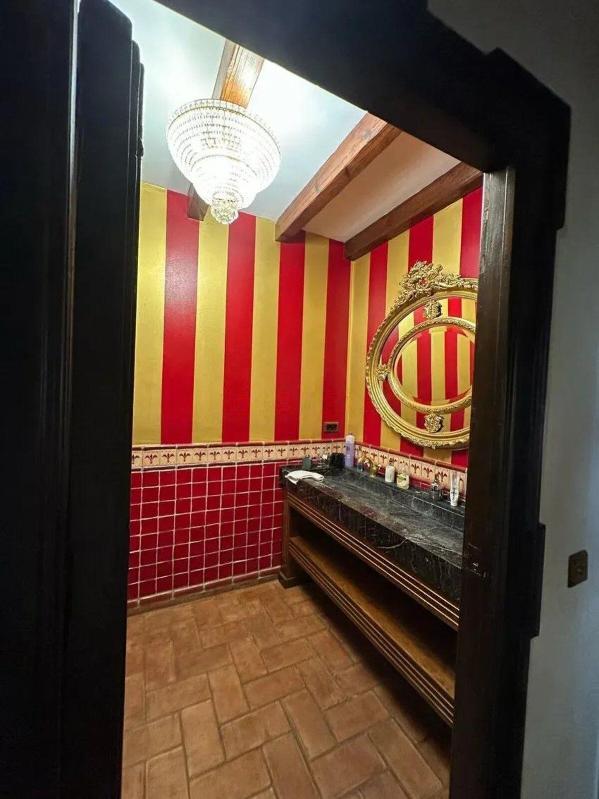 Badkamer met rode en gouden strepen, kroonluchter en marmeren wastafel