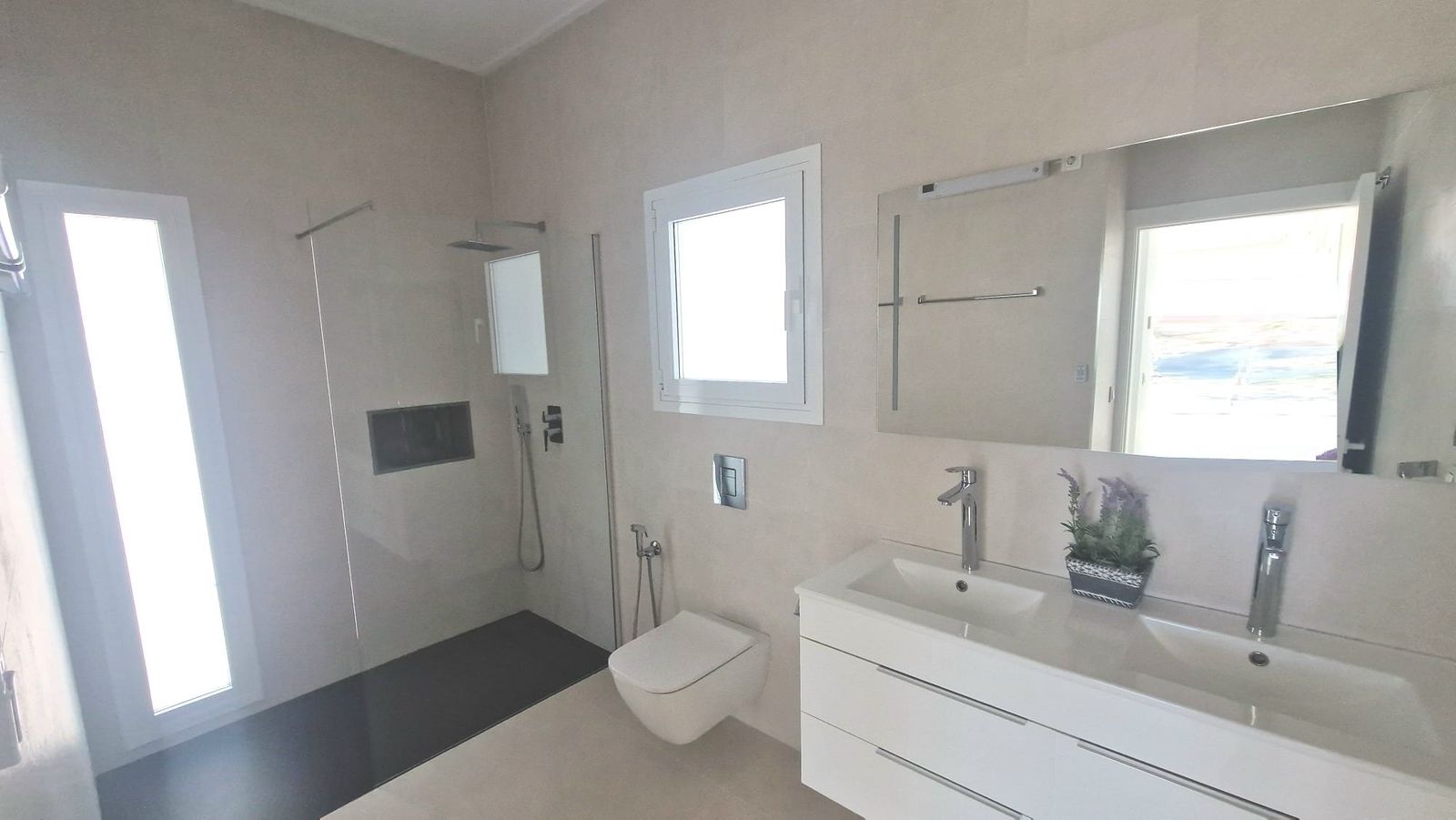 Moderne badkamer met inloopdouche, raam en wastafelmeubel.