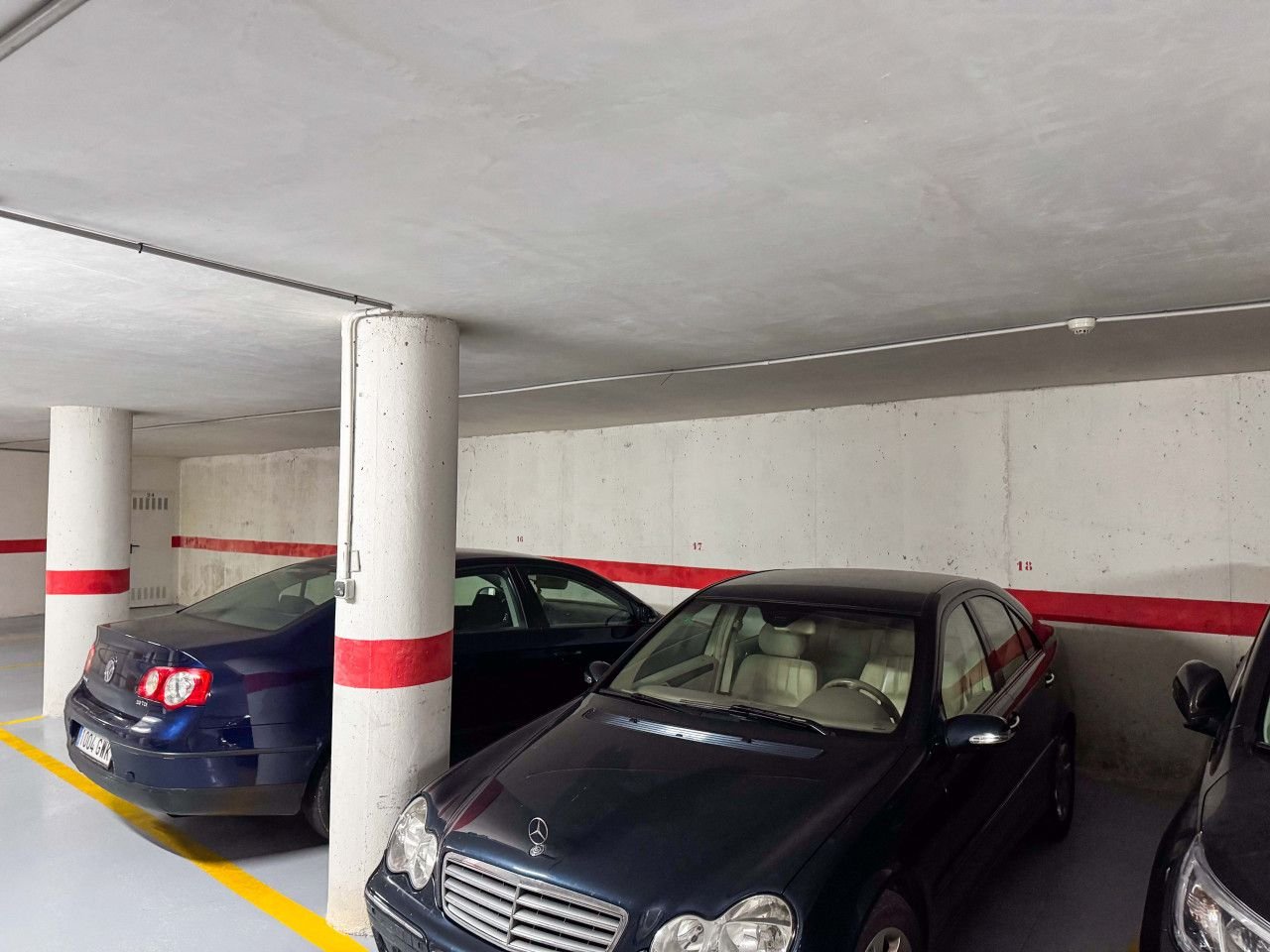 Underground parking garage with three cars parked in designated spaces.