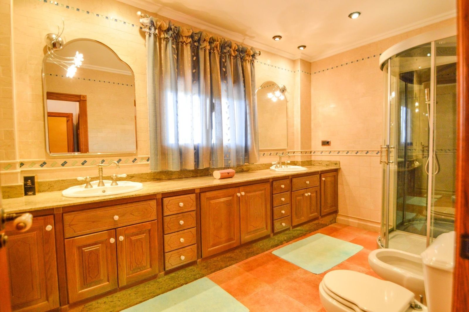 Badkamer met houten kasten, wastafels en douchecabine.