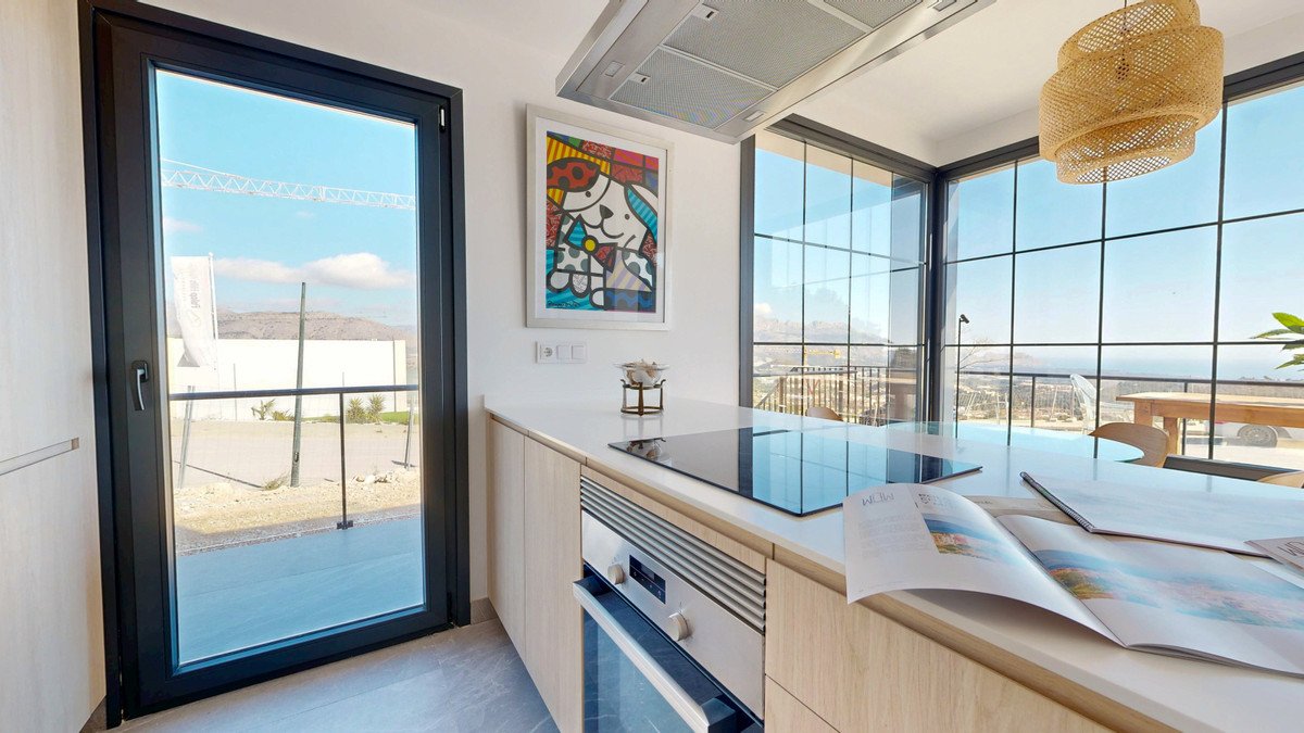 Modern kitchen with island, induction hob, oven, and large windows offering a stunning sea view and artwork on the wall.