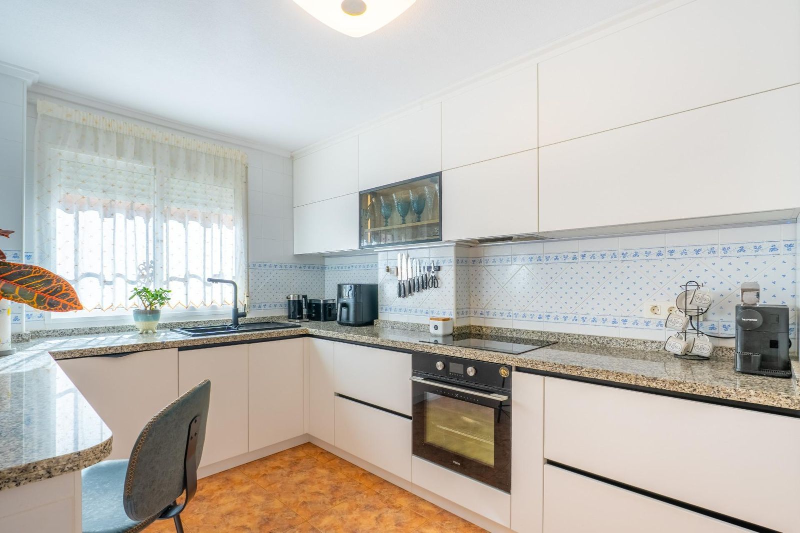 Moderne witte keuken met granito aanrechtblad en betegelde achterwand