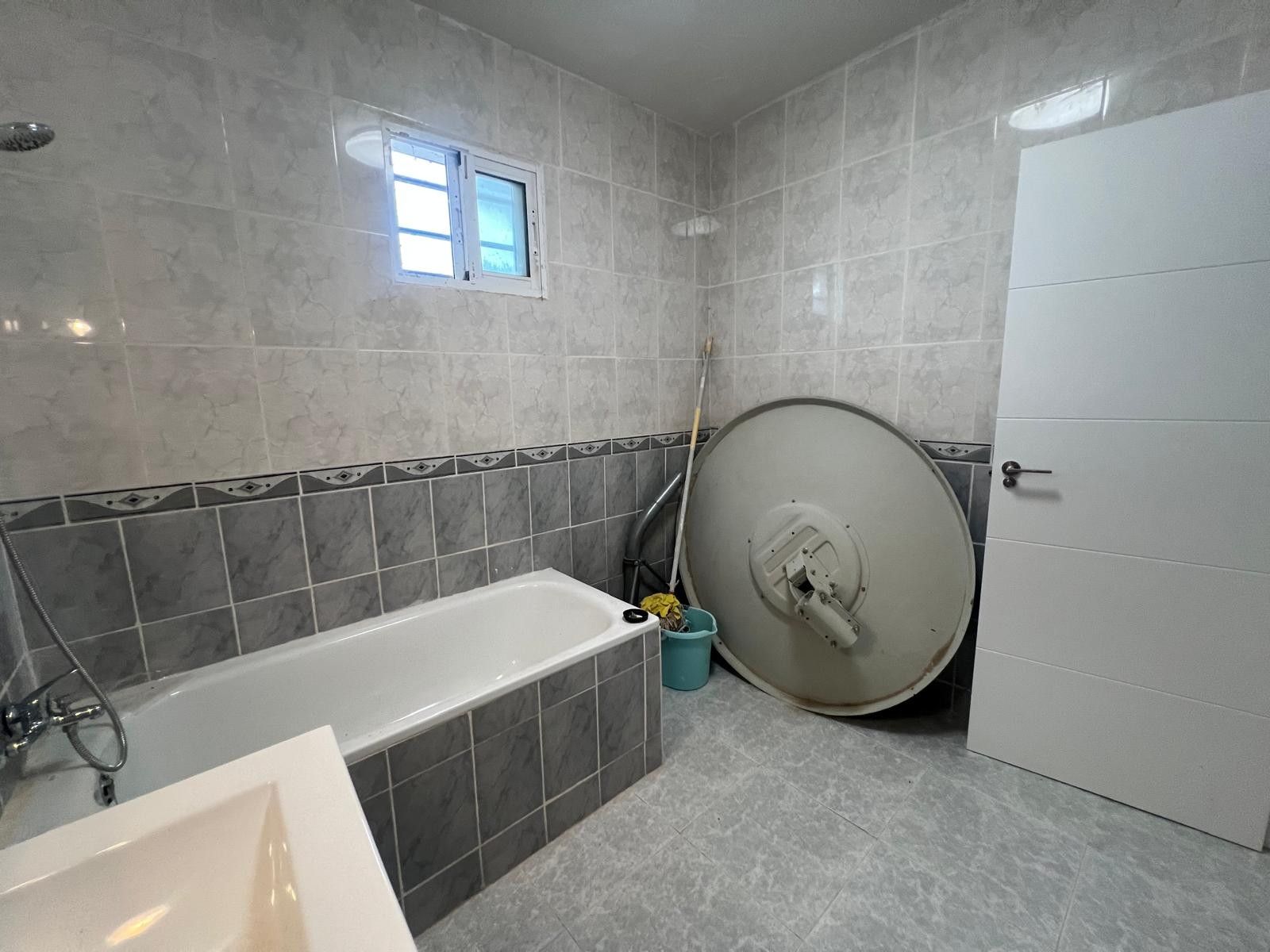 Badkamer met ligbad en schoonmaakapparatuur