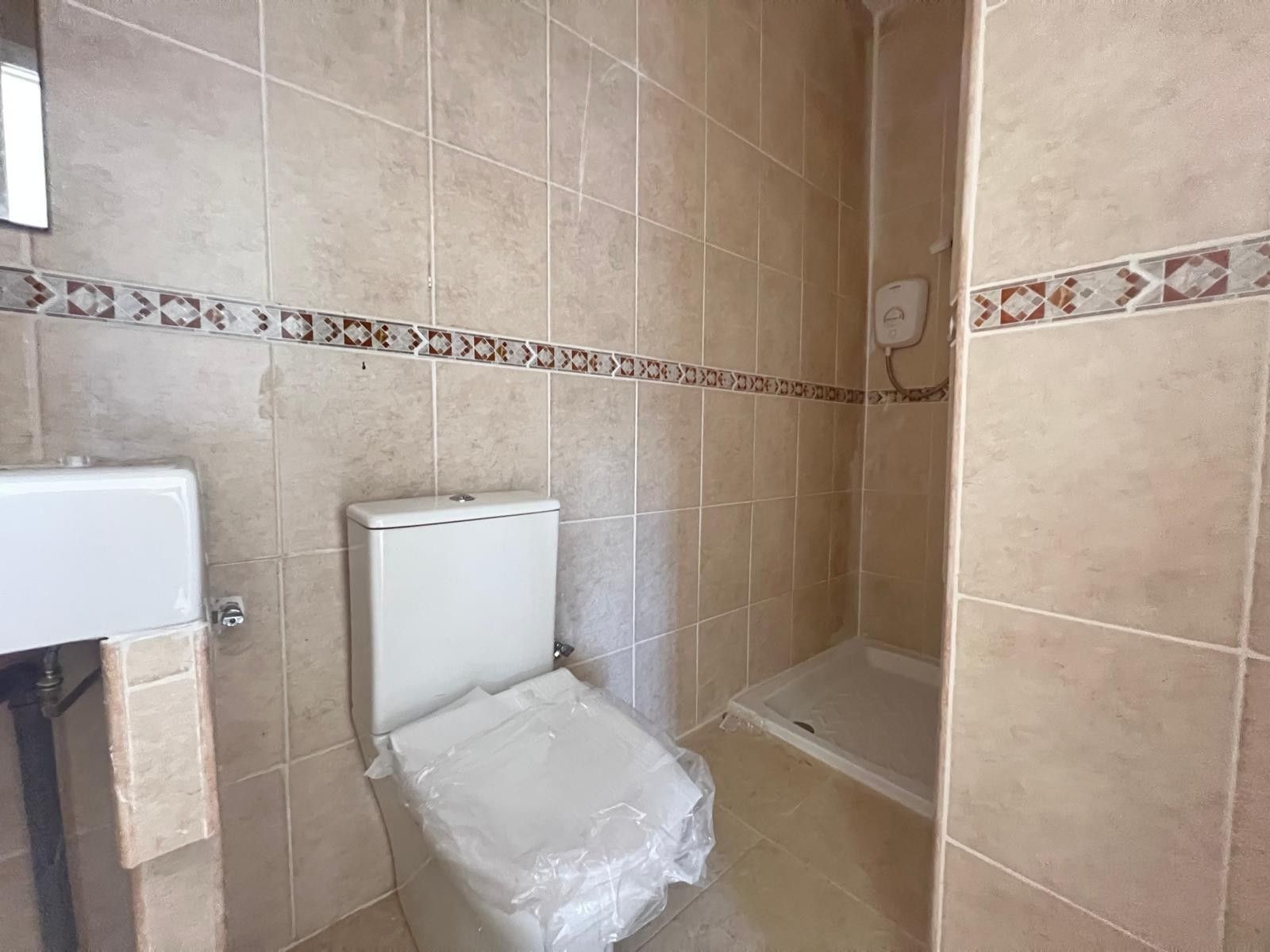 Getegelde badkamer met toilet en douchecabine.