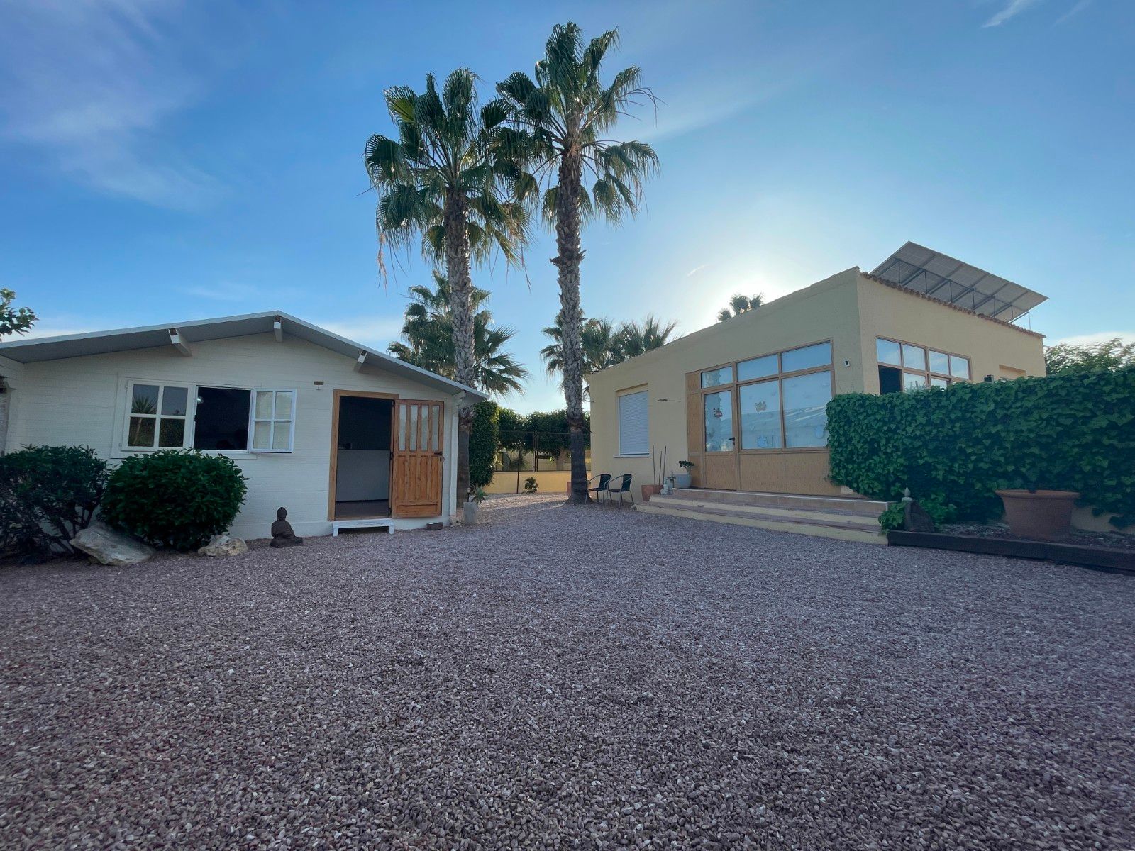 Exterieur van woning met palmbomen en zonlicht