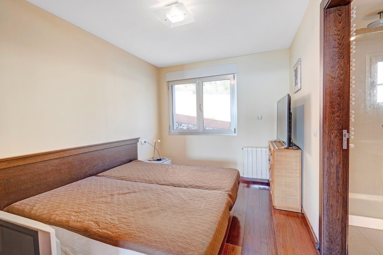 Slaapkamer met twee eenpersoonsbedden, tv en badkamerdeur.