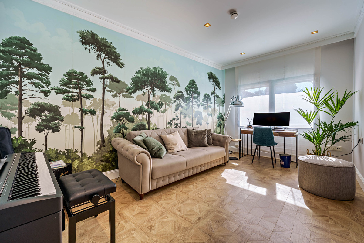 Eclectische woonkamer met bosbehang, piano en bureau.