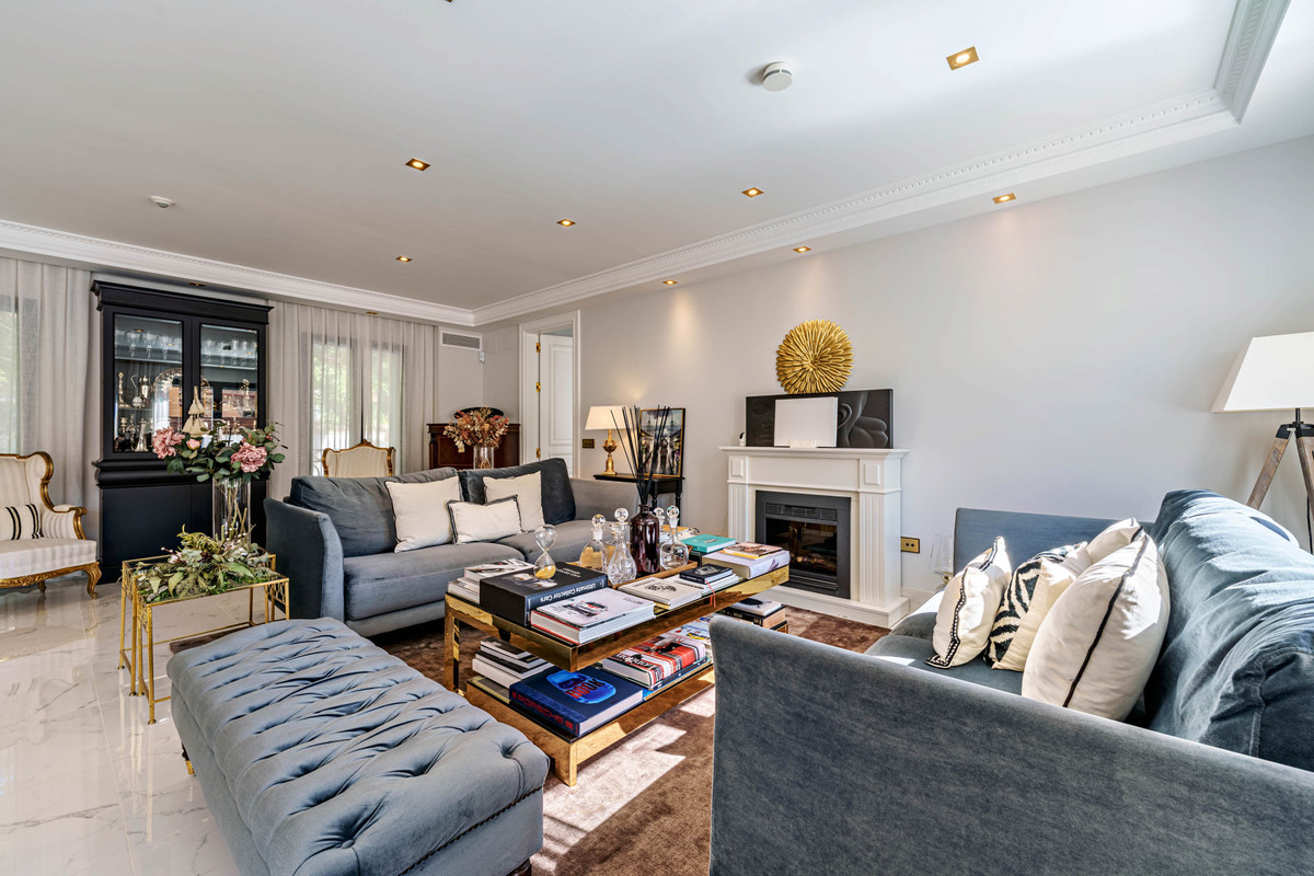 Elegant ingerichte woonkamer met blauwe banken, open haard en gouden accenten.