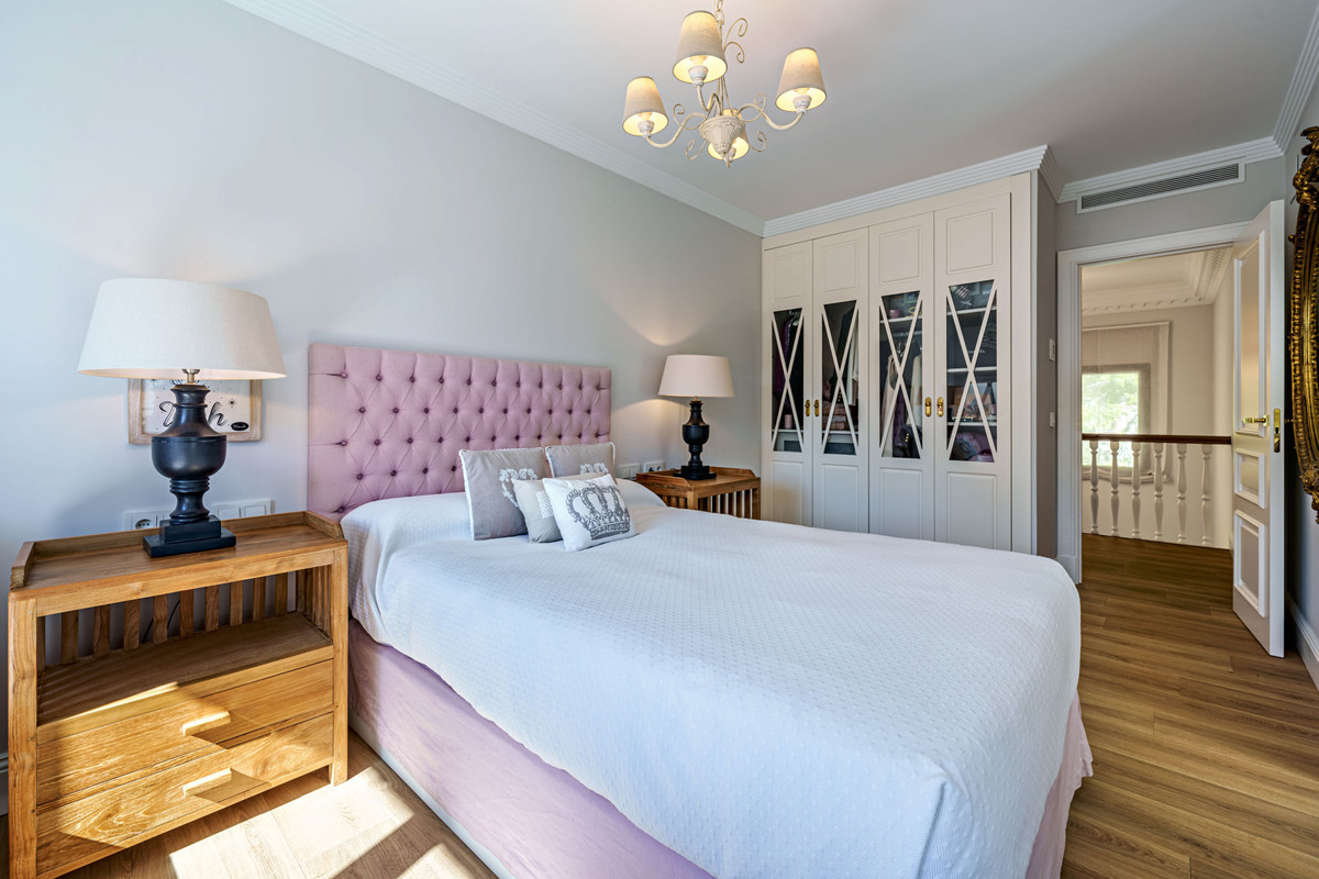 Elegante slaapkamer met roze hoofdeinde en witte kledingkast.