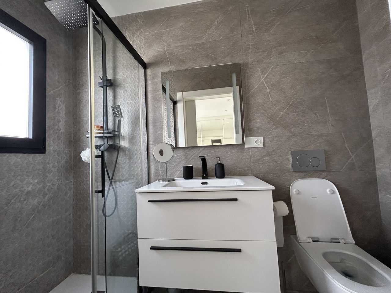 Moderne grijze badkamer met douche, wastafel en toilet.