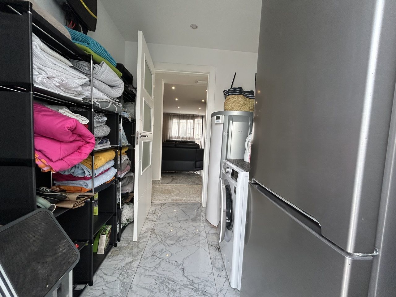 Opbergruimte in de bijkeuken met wasmachine en koelkast.