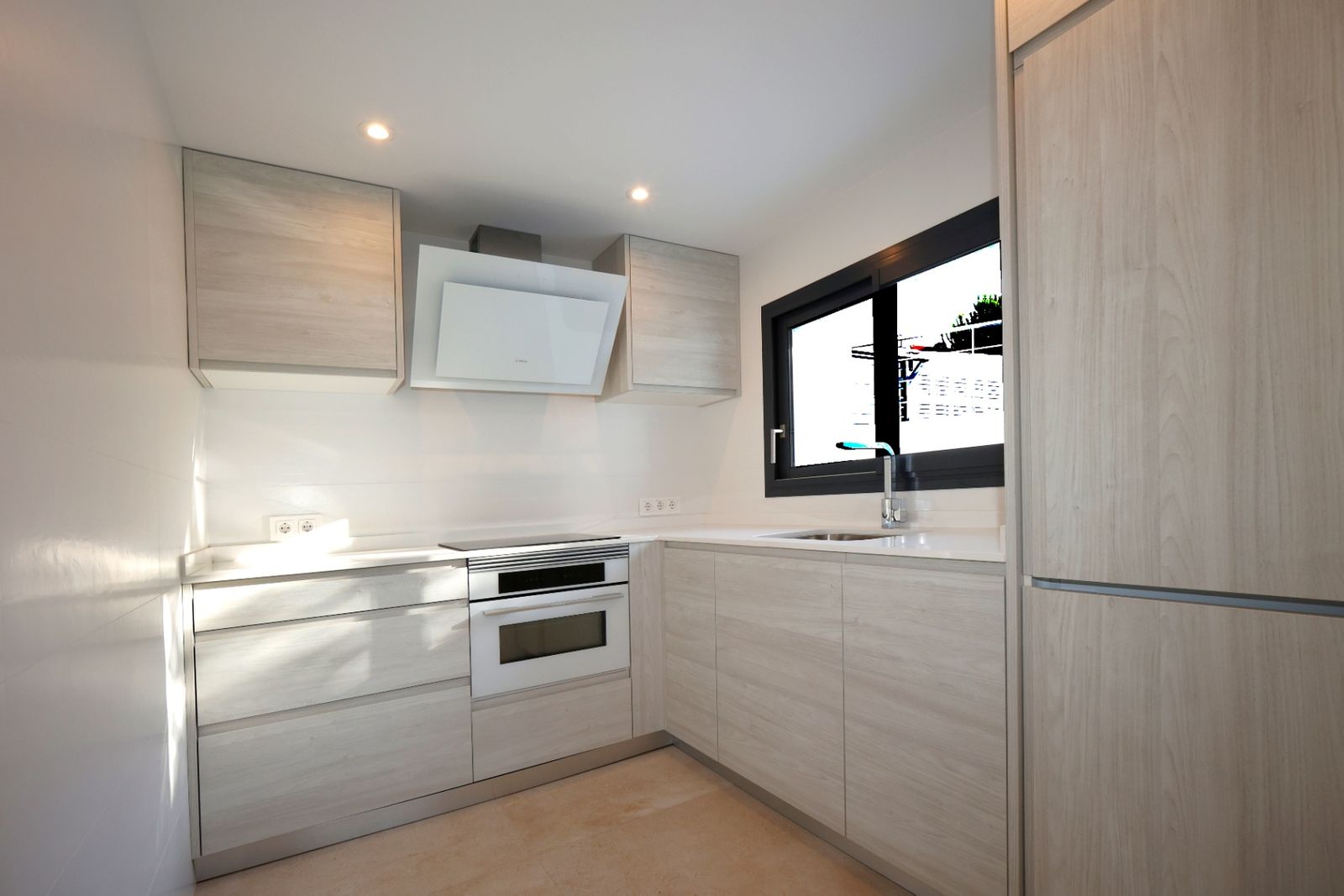 Moderne keuken met houten kasten en een groot raam.