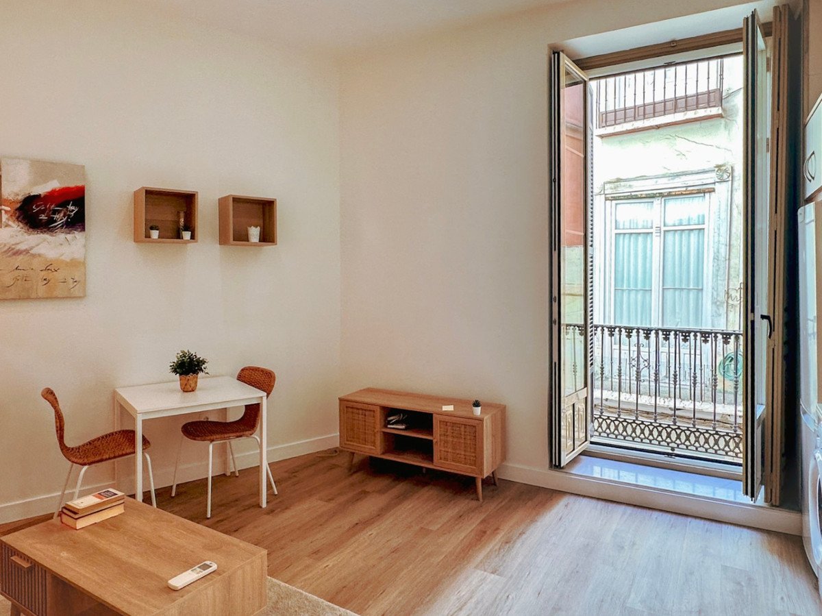 Útulný obývací pokoj s výhledem na balkon, dřevěným nábytkem a moderním dekorem.