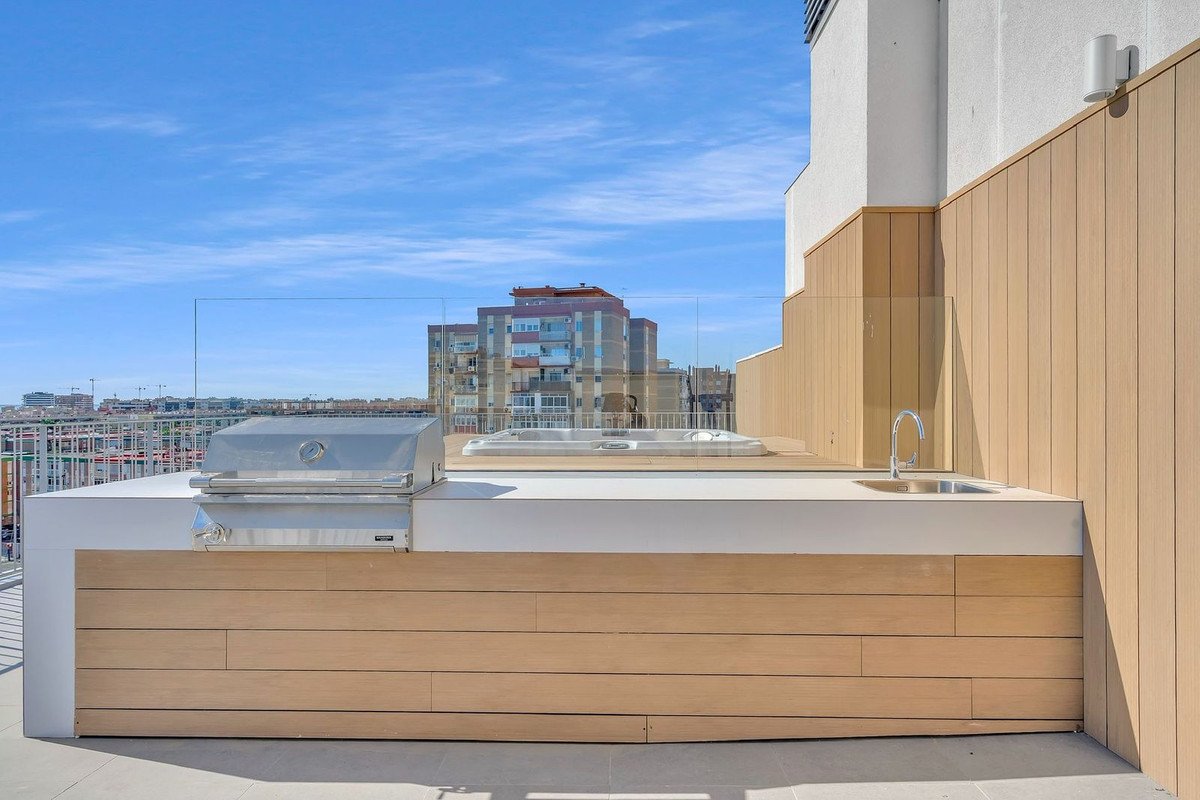 Balcony with city view, outdoor kitchen, sink, grill, and seating area.