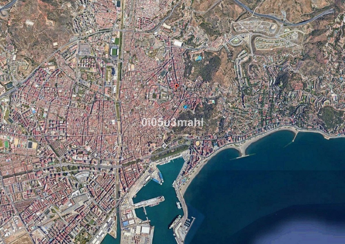 Aerial view of a dense coastal city with a large port and a long sandy beach.