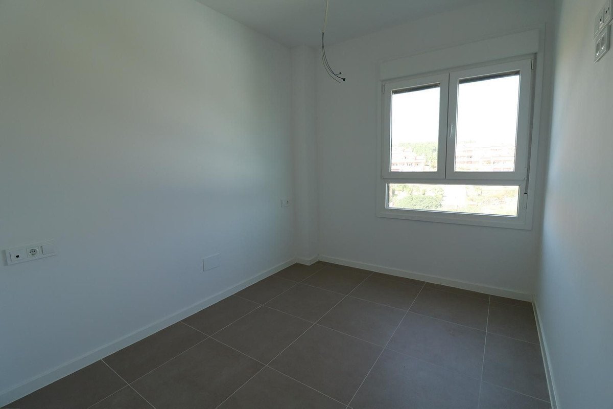 Empty room with tiled floor and a large window showing trees and buildings outside.