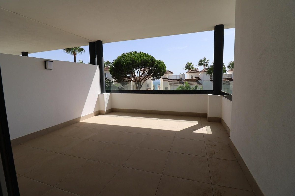 Spacious balcony with tiled floor overlooking townhouses, palm trees, and a large tree on a sunny day.