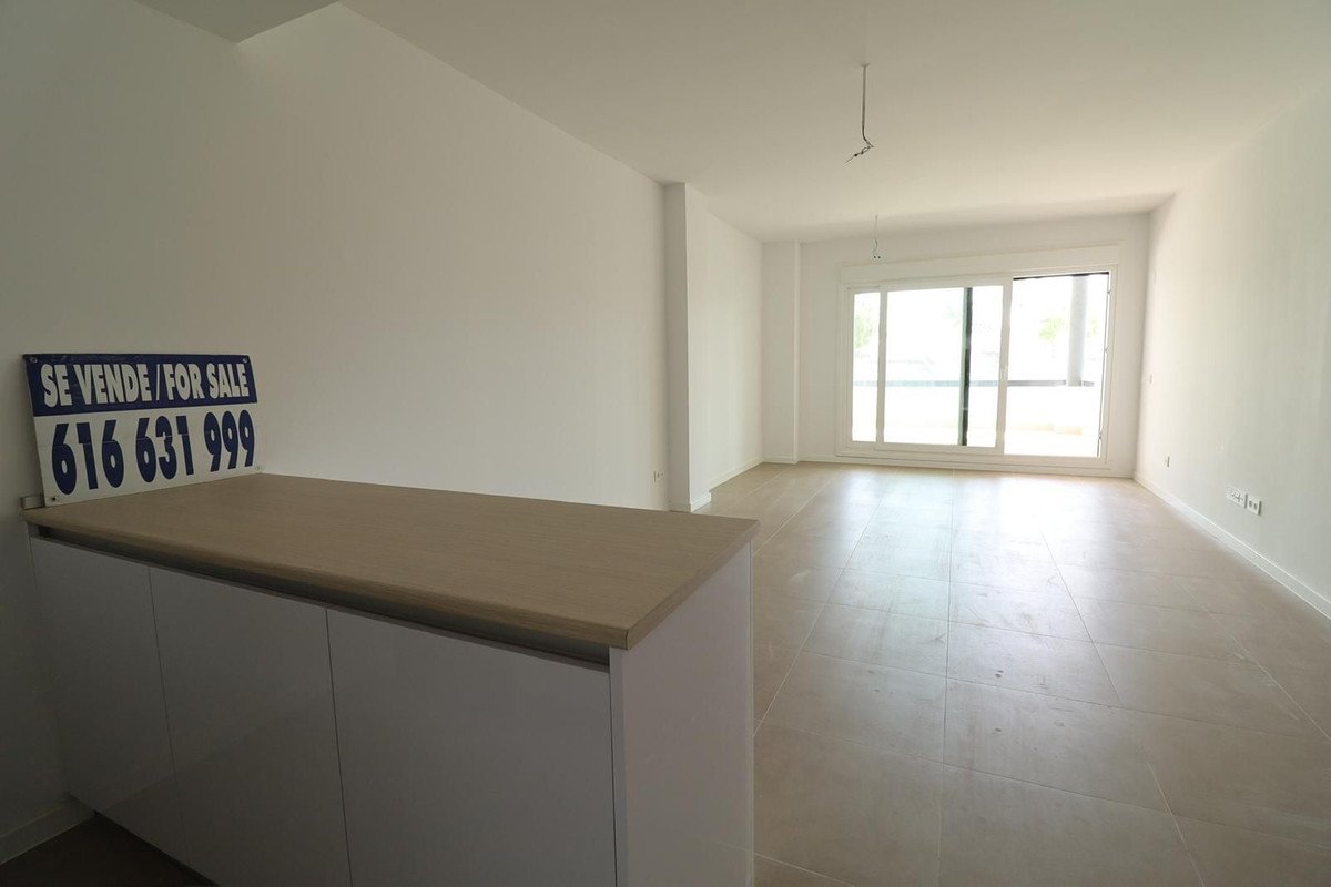 Empty modern living room with a large sliding glass door offering natural light and a contemporary built-in cabinet with a 'for sale' sign.