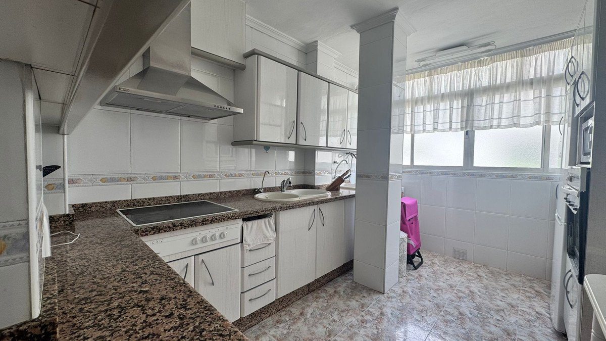 Modern kitchen with white cabinets, granite countertops, and tiled walls.