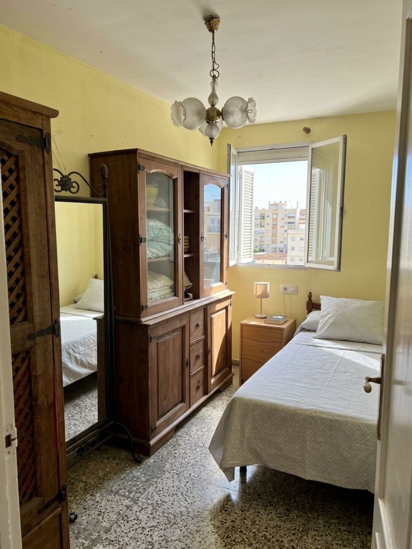 Bedroom with yellow walls, city view, wooden furniture, and large window