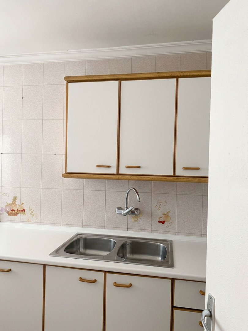 Kitchen with white cabinets, tiled wall, and double sink