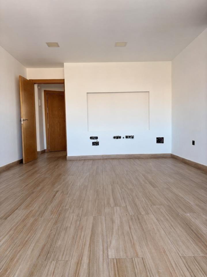 Empty living room with wood-look tile flooring and a built-in wall feature with pre-wired outlets.